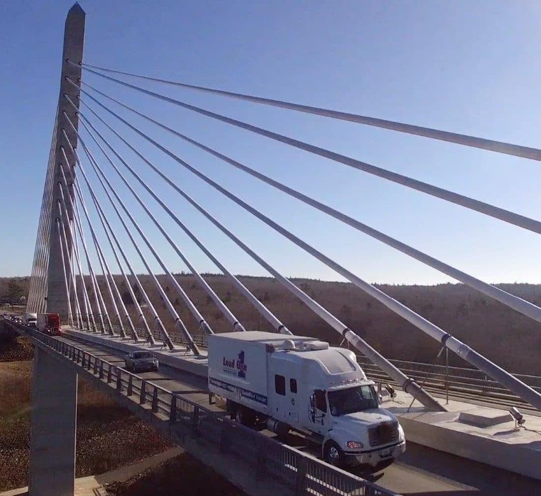 A Load One straight truck crossing a cable-stayed bridge under a clear sky